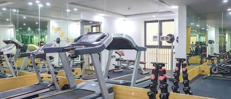 Un gimnasio con cintas de correr, máquinas de pesas y pesas sueltas.