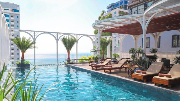 A poolside area with lounge chairs and a view of the sea. - Golden Lotus Luxury Hotel Da Nang (Da Nang)