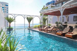 A poolside area with lounge chairs and a view of the sea. - Golden Lotus Luxury Hotel Da Nang (Da Nang)