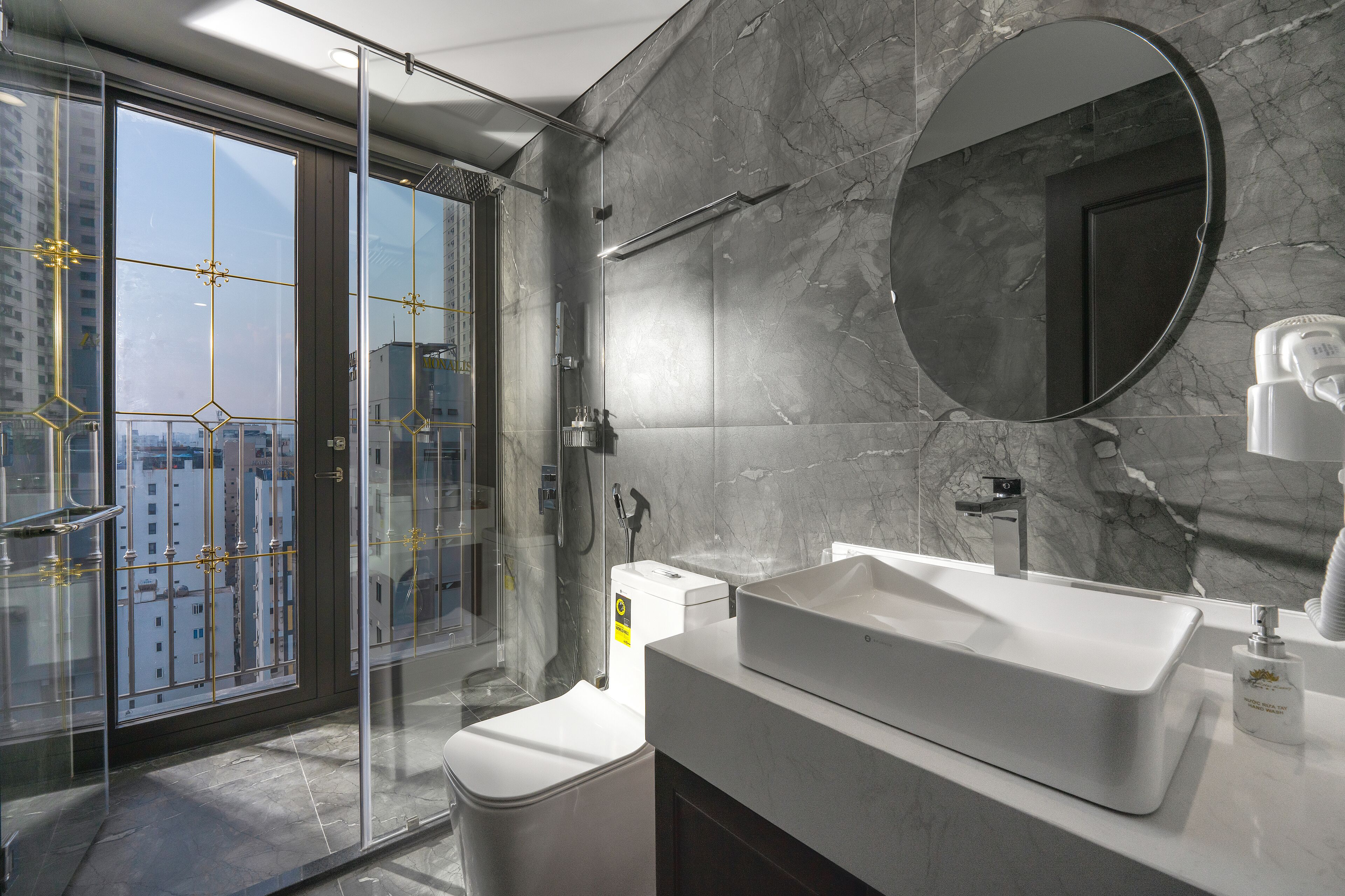 A modern bathroom with a large mirror, a white sink, and a glass-enclosed shower.