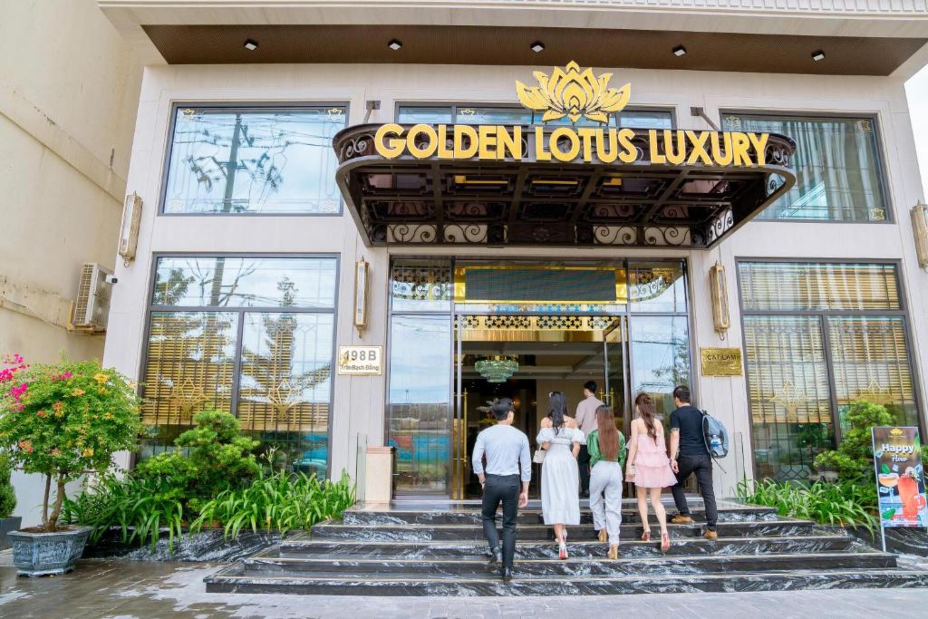 The entrance to the Golden Lotus Luxury hotel with a prominent sign, steps leading up to the entrance, and a few people entering.