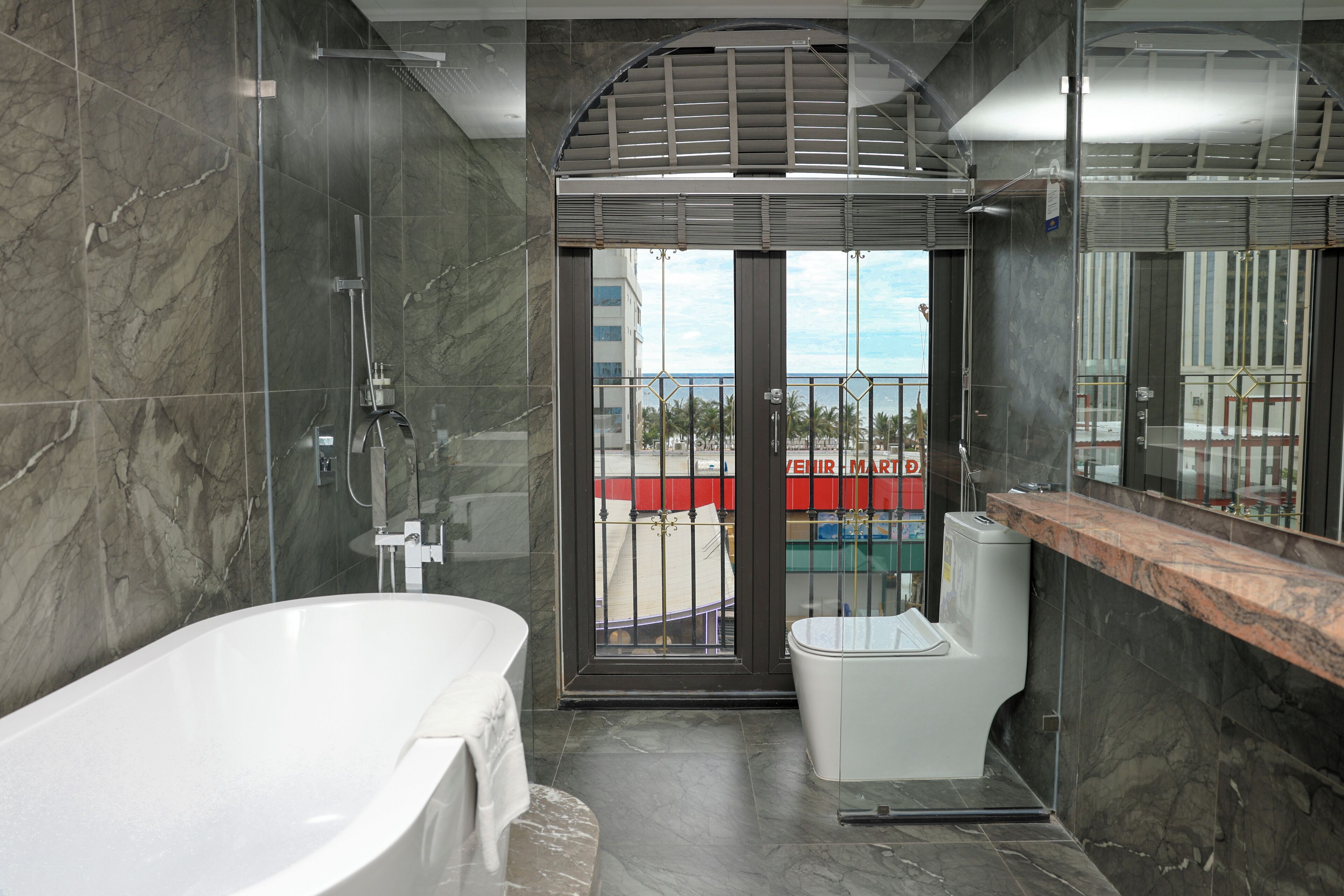 Et moderne badeværelse med badekar, toilet og et bruseområde med glasvægge.