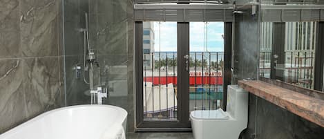 Un baño moderno con bañera, inodoro y zona de ducha con mampara de cristal.