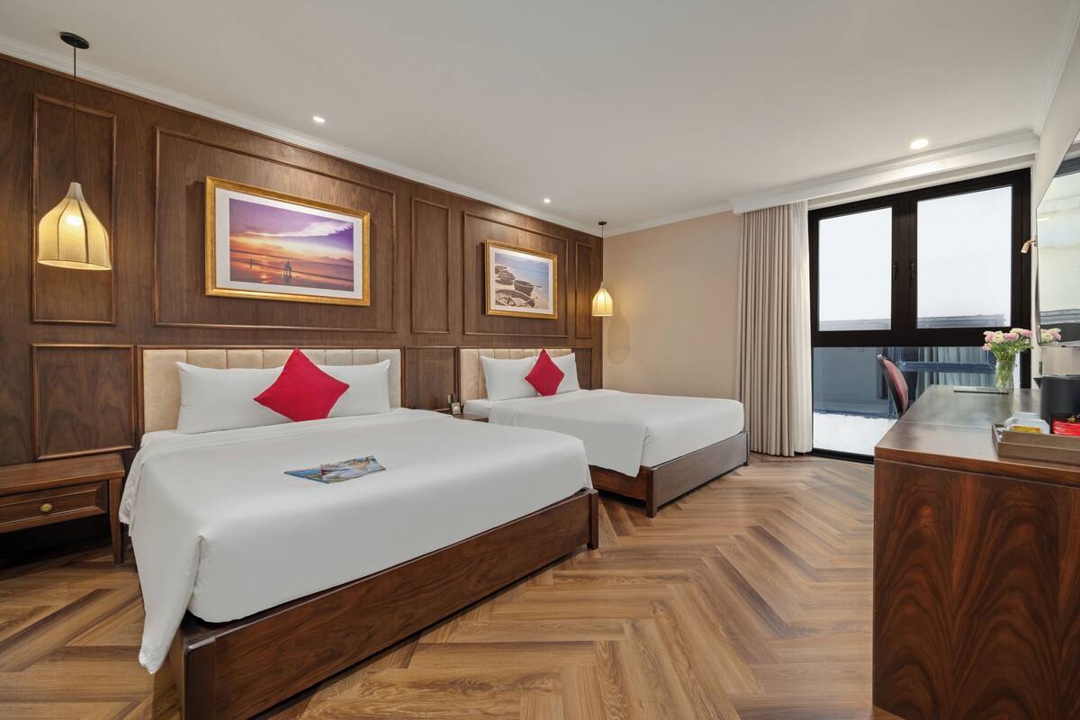 A hotel room with two beds, wooden paneling, and large windows.