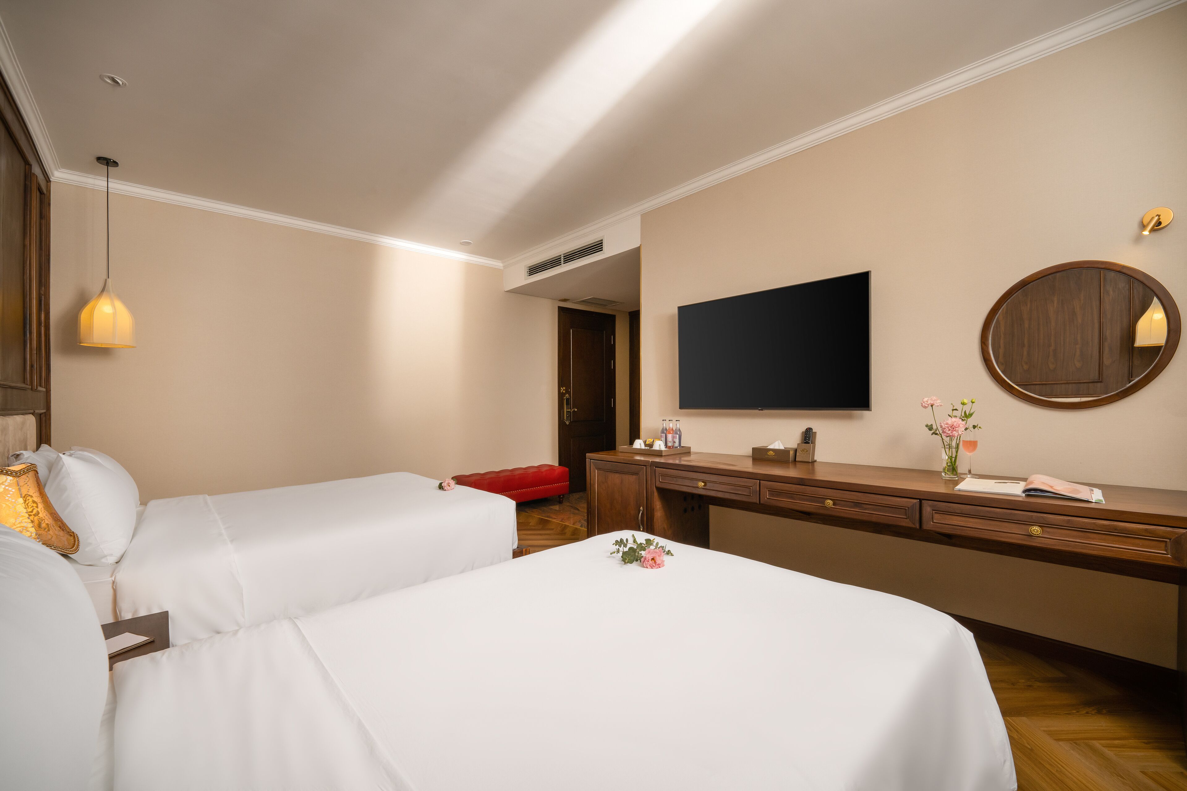 Een hotelkamer met twee bedden, een bureau, een televisie en een spiegel.