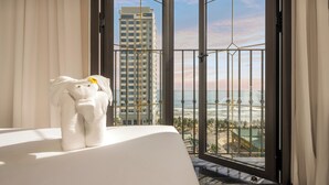 A hotel room with a view of the ocean and a tall building. - Golden Lotus Luxury Hotel Da Nang (Da Nang)