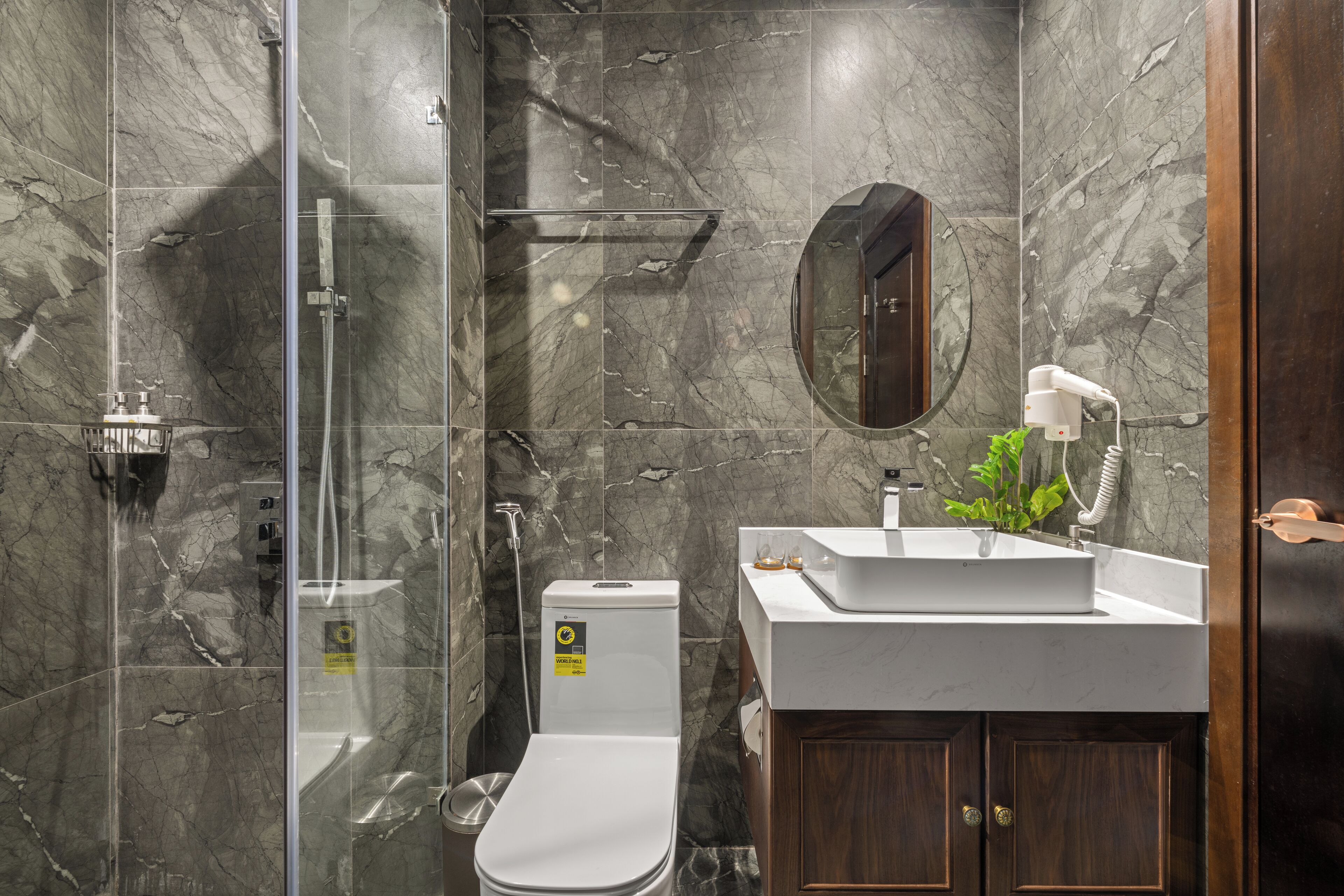 A modern bathroom with a glass-enclosed shower, a toilet, and a sink with a mirror above it.