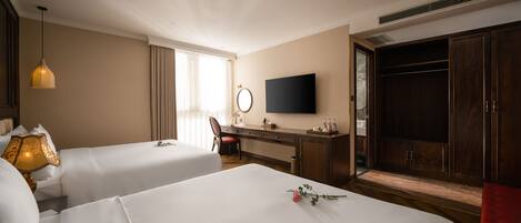 A hotel room with two beds, a desk, a television, and a wardrobe.