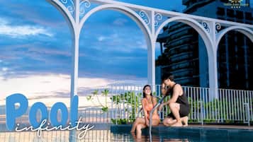 Zona de piscina con una estructura moderna en arco y vista de un edificio al fondo.