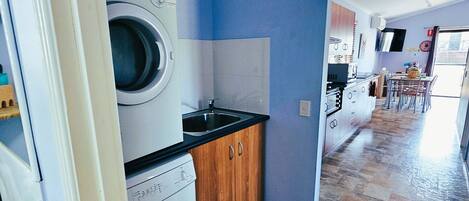 A laundry area with a washing machine and dryer, a sink, and wooden cabinets.