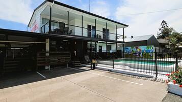 Un motel doté d’une façade en verre, d’un espace extérieur aménagé pour s’asseoir et d’un espace piscine.