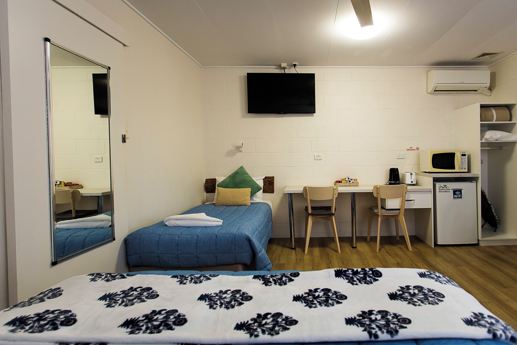 Une chambre comprenant un lit, un bureau, une chaise, une télévision et un réfrigérateur.