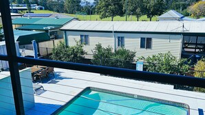 A residential area with a swimming pool, a fenced deck, and a house with a green roof. - Kilcoy Motel (Kilcoy)