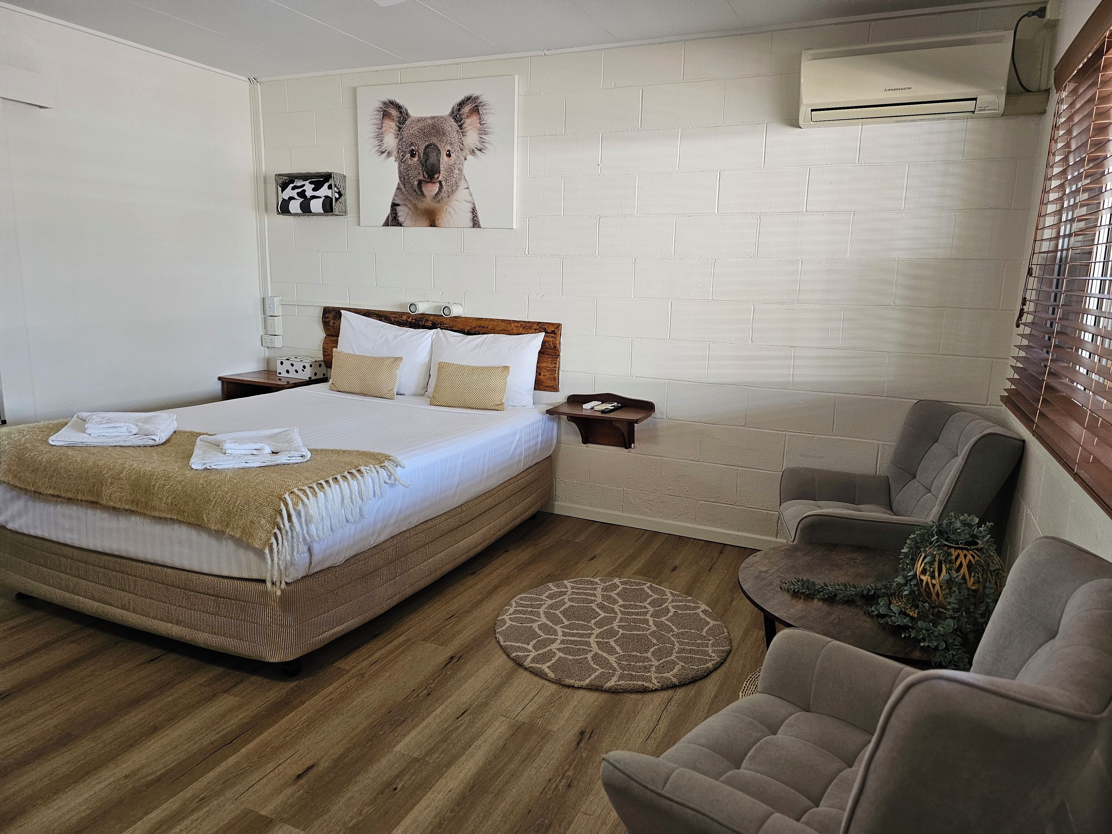Una camera da letto ordinata con un letto, un comodino, una sedia e un tappeto rotondo.