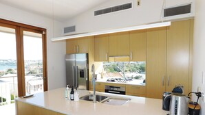 Una cocina moderna con un refrigerador de acero inoxidable, un horno empotrado y una cafetera.