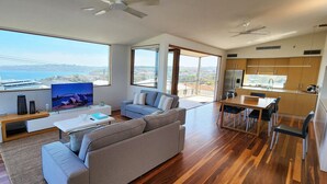 Una sala de estar moderna con un televisor grande, un sofá, un comedor y una cocina.