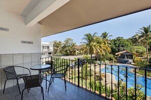 A balcony with a pool view, outdoor seating, and a sign that reads 'PURA VIDA.' - Amazing Condo! Playas del Coco (Provincia de Guanacaste)