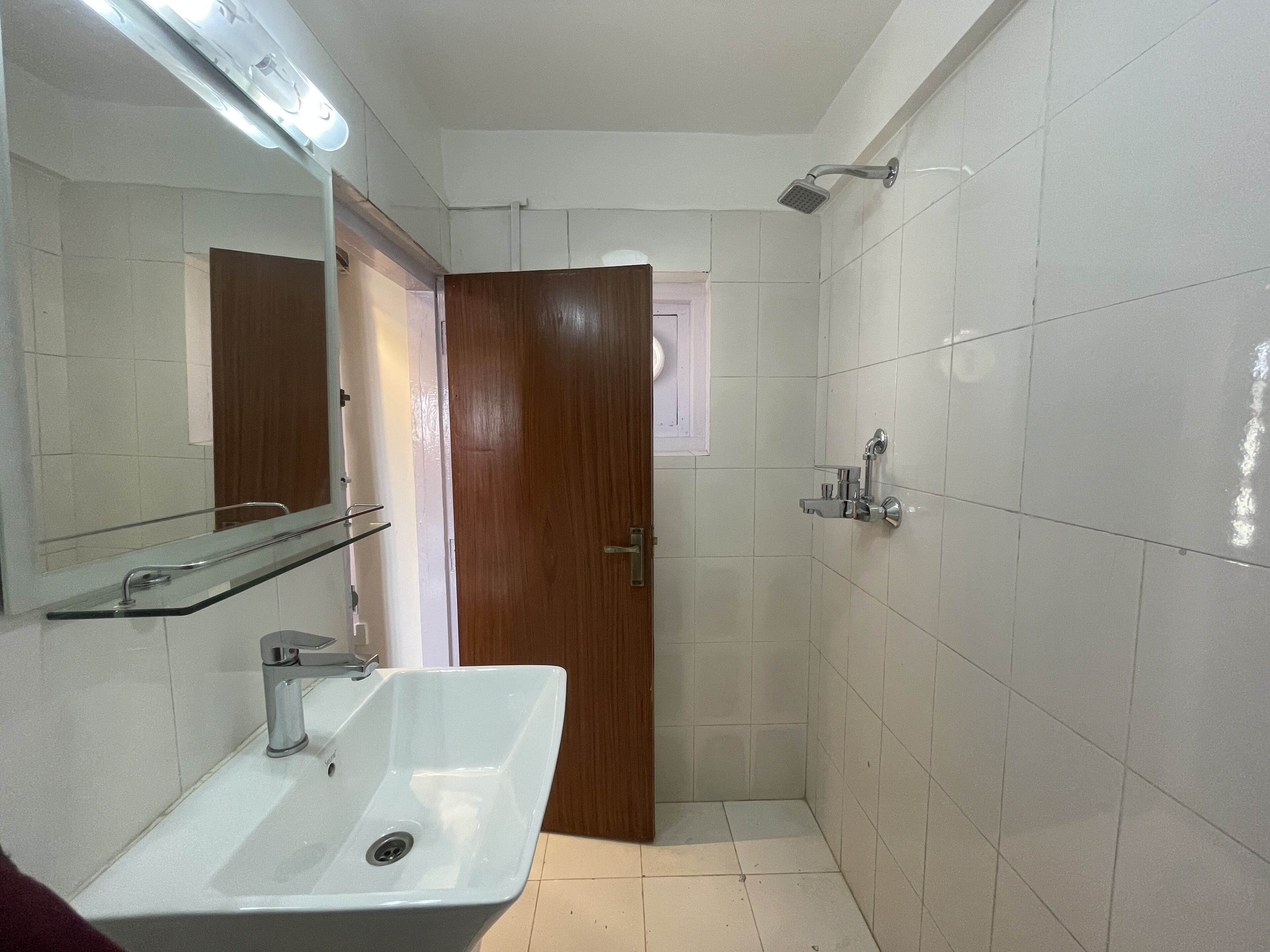 A bathroom with a white sink, mirror, and shower.