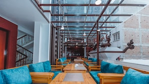 Un interior moderno con mesas de madera, asientos acolchados en azul, ventanas amplias y una pared de ladrillo.