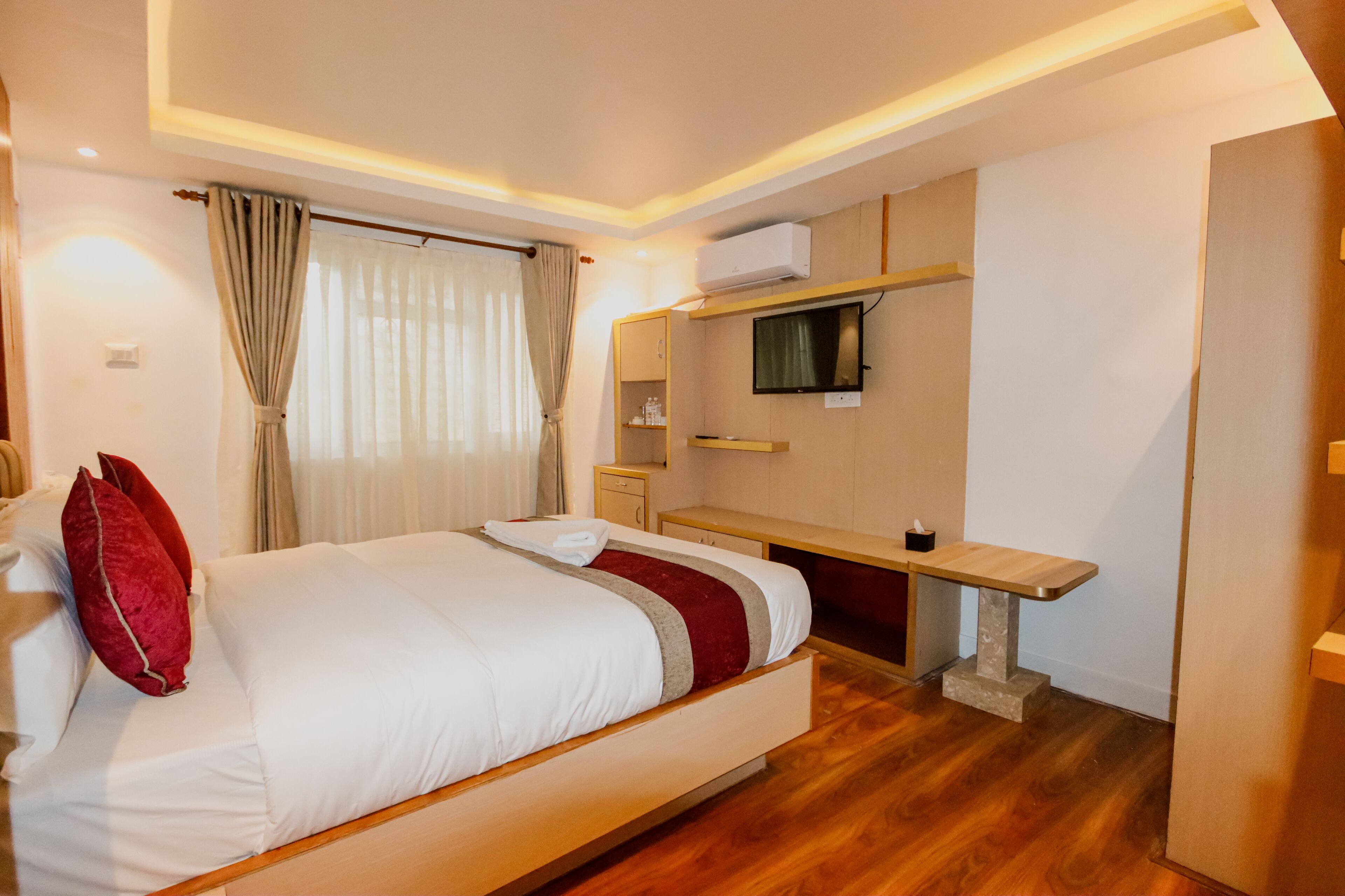 Quarto de hotel moderno com uma cama grande, uma escrivaninha e uma televisão na parede.