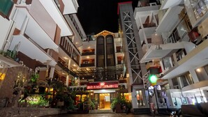 Un hotel con entrada principal, varios pisos y balcones.
