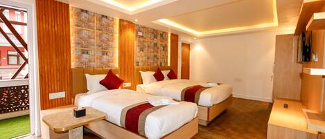 A hotel room with two beds, wooden flooring, a small table, and a wall with a patterned design.