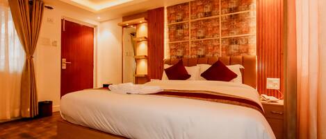 A hotel room with a large bed, wooden headboard, and a wall with a patterned design.
