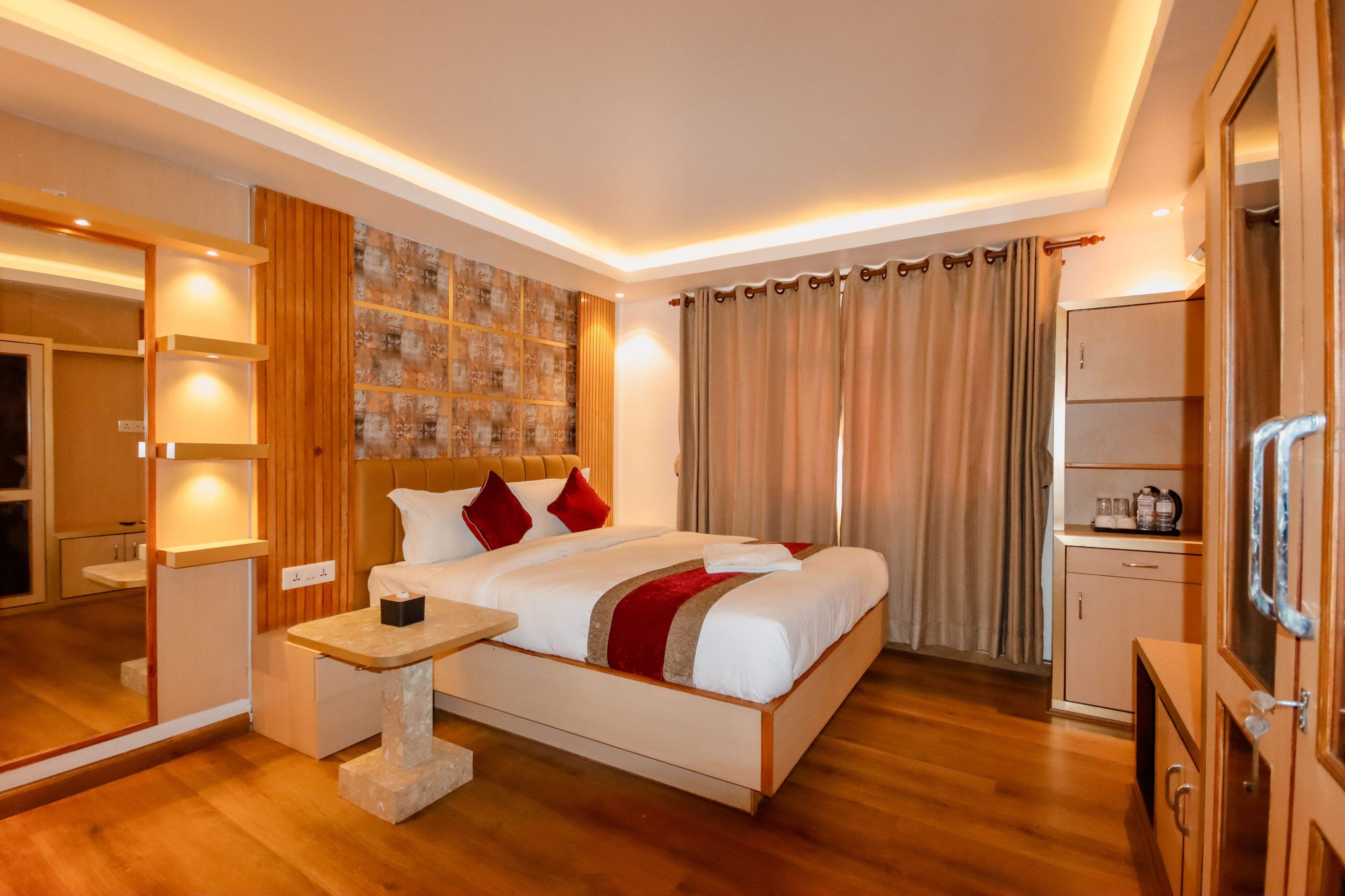 A modern hotel room with a large bed, bedside table, and a wardrobe.