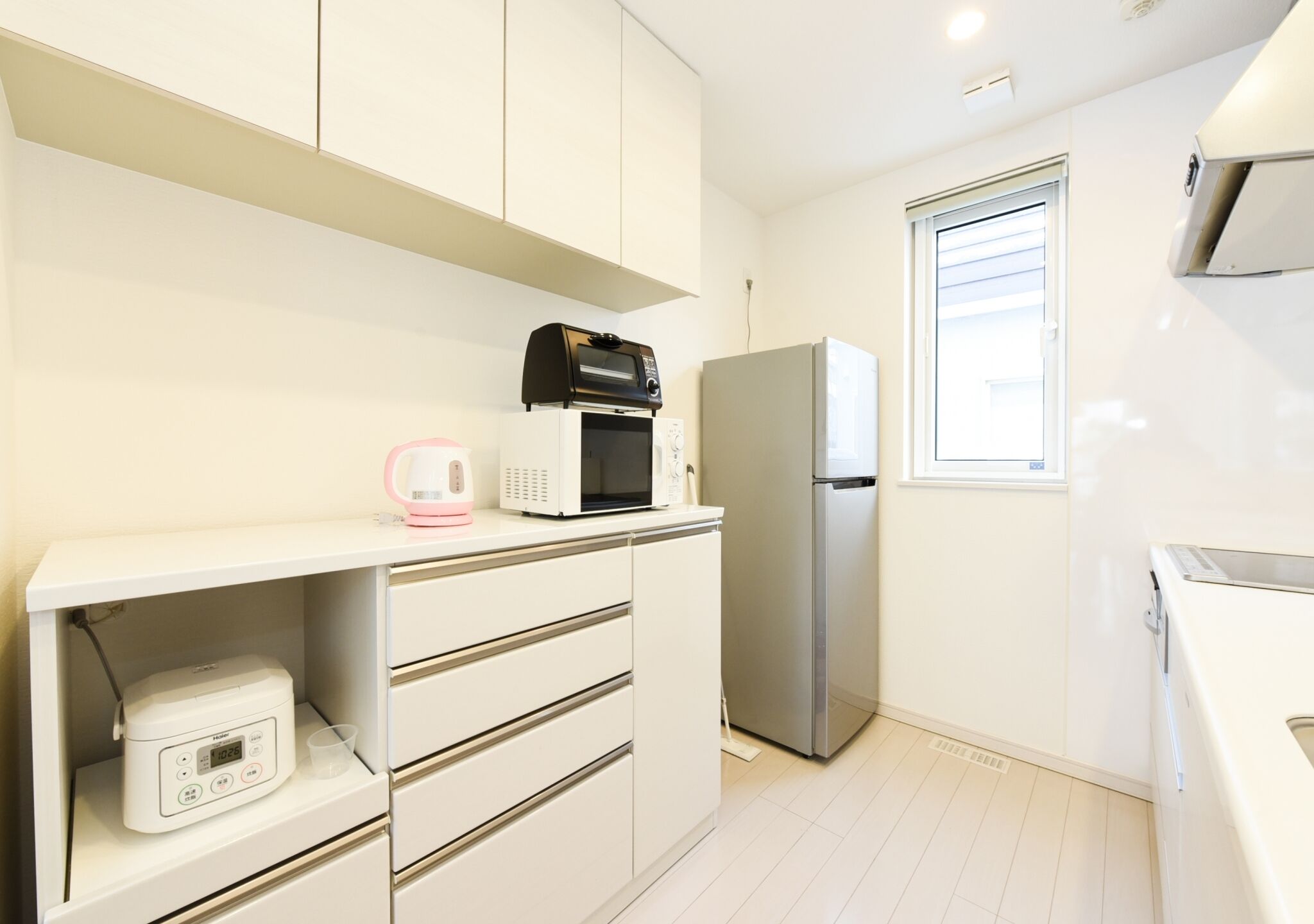 A modern kitchen with white cabinets, a microwave, a refrigerator, and a built-in oven.