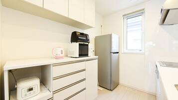 A modern kitchen with white cabinets, a microwave, a refrigerator, and a built-in oven.