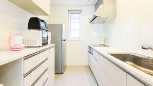 A modern kitchen with white cabinets, a stainless steel sink, a microwave, and a refrigerator. - S12 HOTEL (Sapporo)