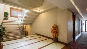 Un vestíbulo amplio con una escalera, plantas en macetas y una alfombra estampada.