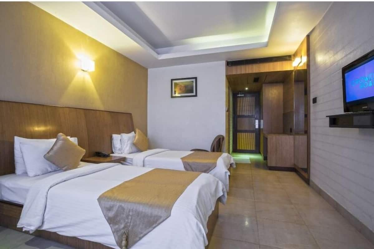 Habitación de hotel con dos camas, un televisor y una lámpara fijada a la pared.