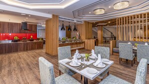 A modern dining area with a central table set for four, surrounded by upholstered chairs. - Fortune Khajjiar - Member ITC Hotels' Group (Chamba)