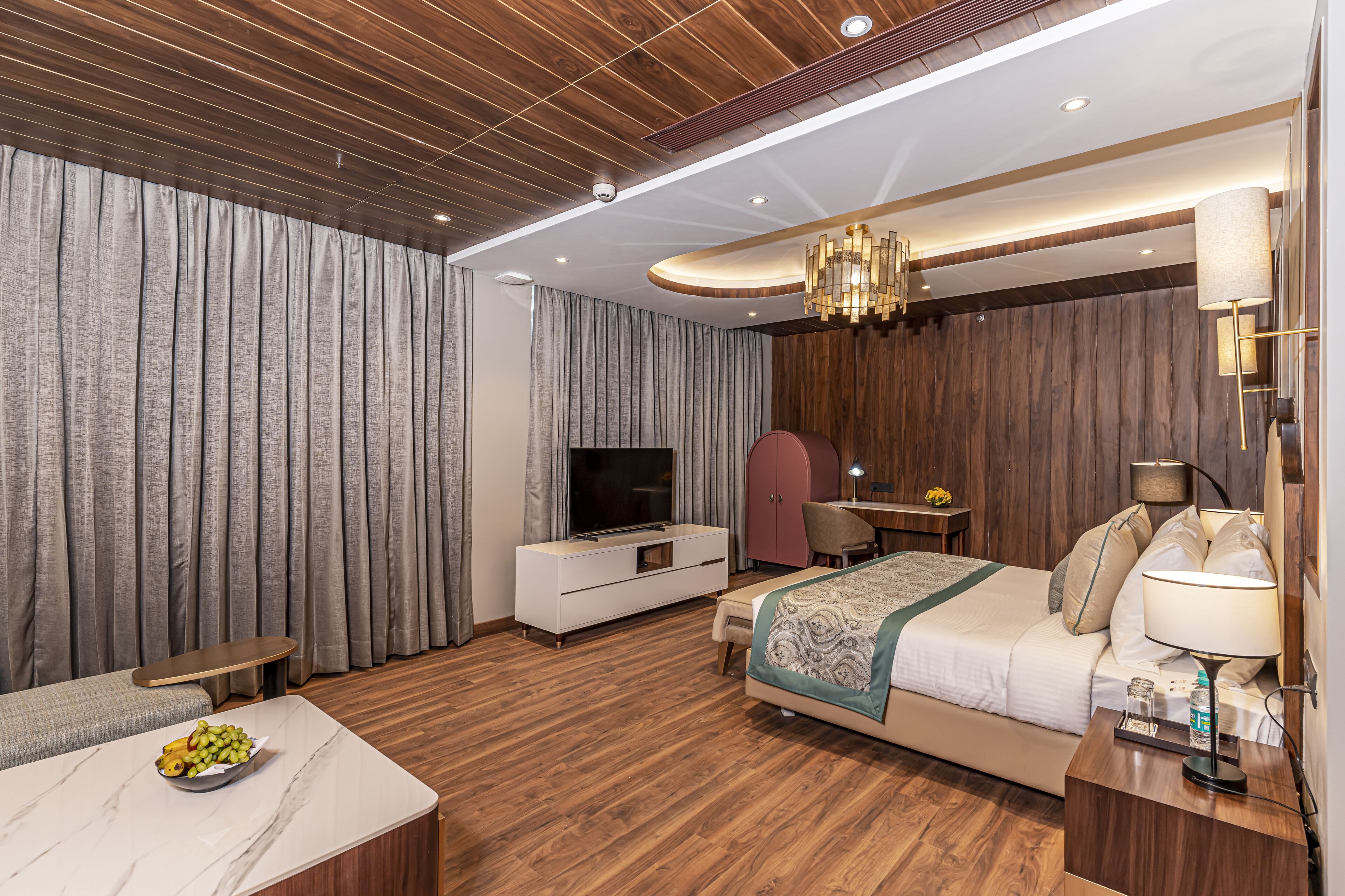Une chambre d’hôtel moderne avec un plafond en bois, un grand lit, une télévision, un bureau et un coin repas.