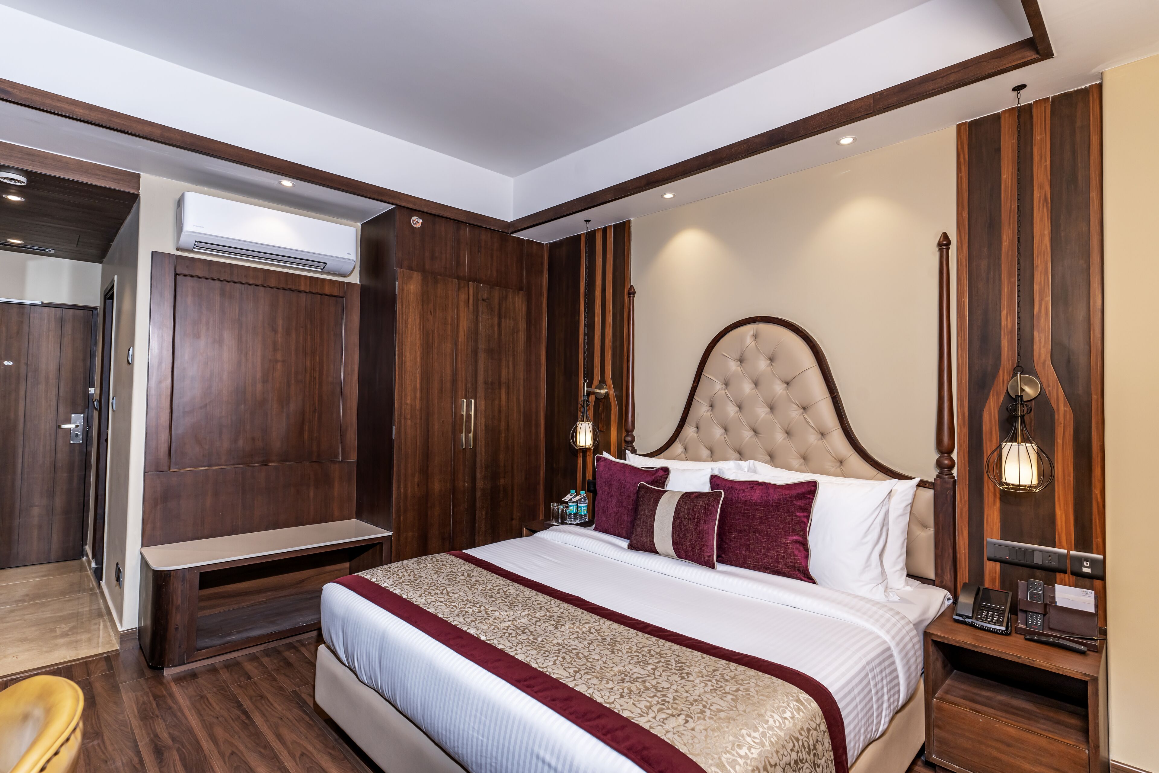 A spacious bedroom with a large bed, wooden wardrobe, and a bedside table with a lamp.