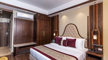 A spacious bedroom with a large bed, wooden wardrobe, and a bedside table with a lamp.