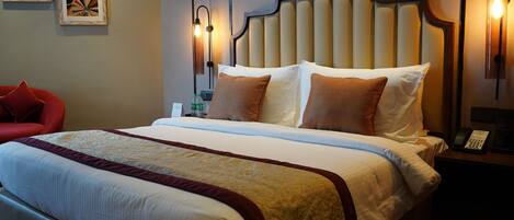 Una habitación de hotel con una cama grande, una mesita de noche con un teléfono y una silla roja.