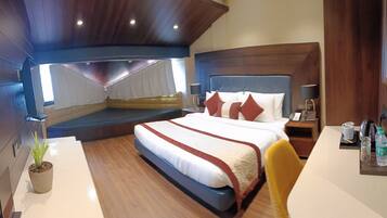 Ein modernes Hotelzimmer mit einem großen Bett, einer Sitzecke, einem Schreibtisch und einer Zimmerpflanze.