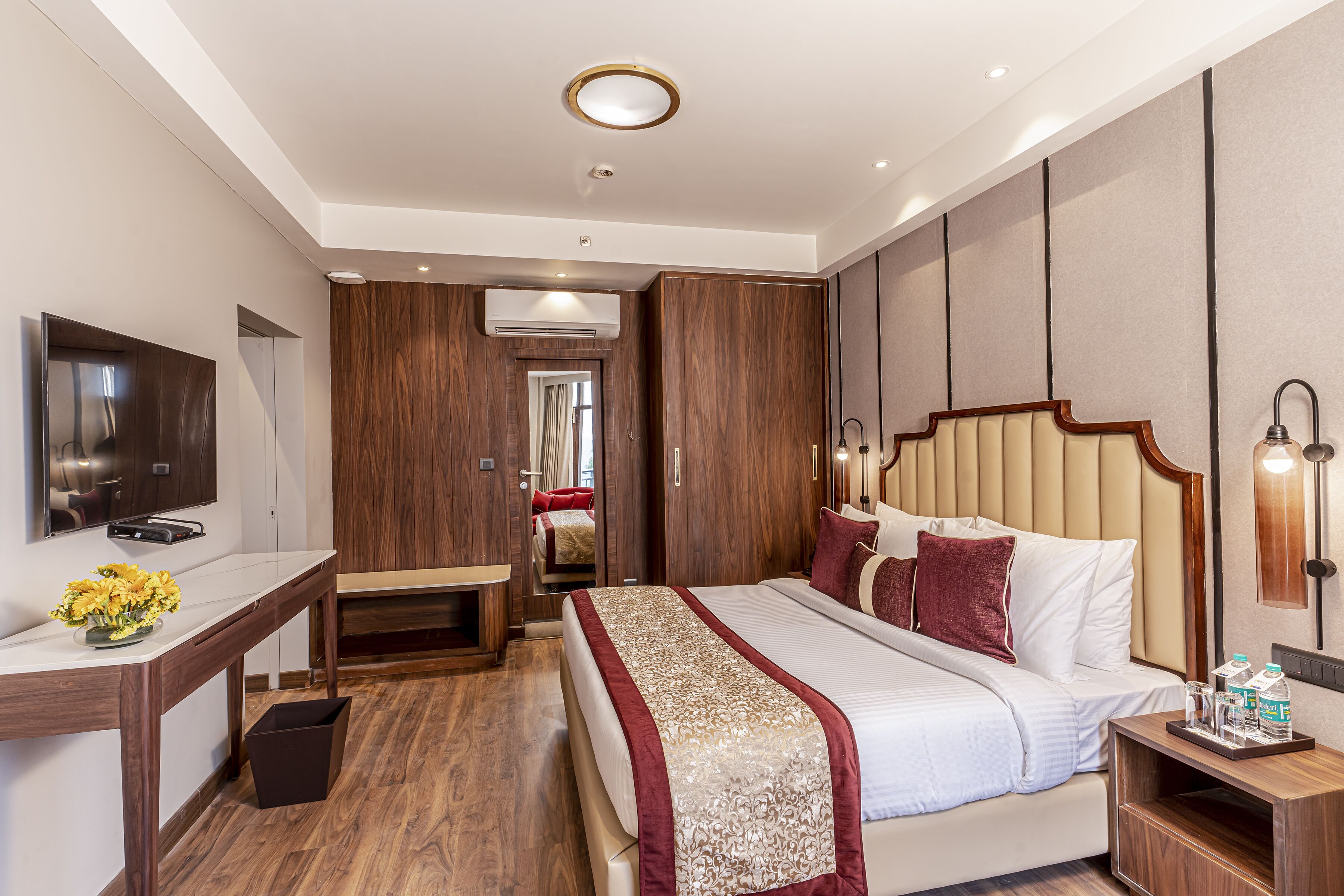Une chambre d’hôtel moderne, dotée d’un grand lit, d’un bureau, d’une télévision et d’une salle de bain visible à travers une porte.