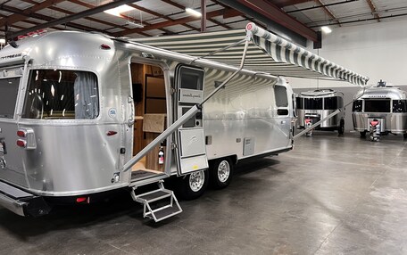 A large, modern RV with a covered sleeping area and a step-up platform.