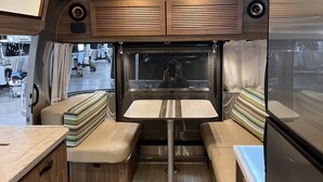 A compact RV interior with a kitchenette, seating area, and a large window. - Affordable Rare Tommy bahama skeeps 2+ in half moon bay (Mill Valley)