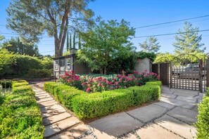 Stroll through the beautifully maintained garden, featuring trimmed hedges and a variety of flowering plants.