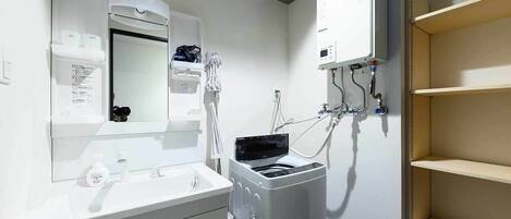 A bathroom with a white sink, mirror, and a wall-mounted heater.