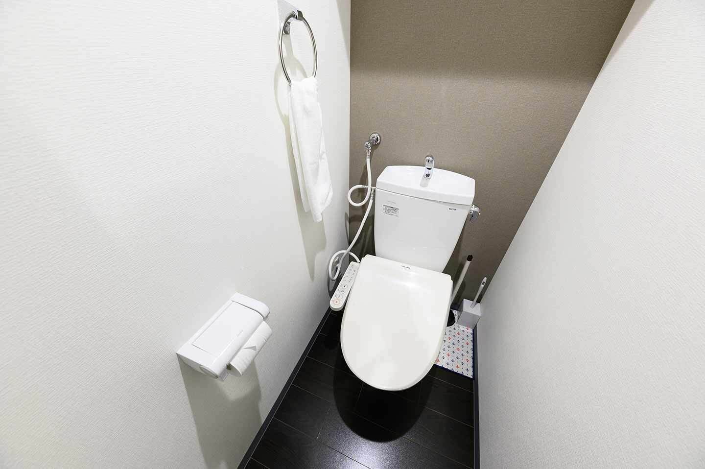 Et lille, moderne badeværelse med toilet, bidet og et håndklædestativ.