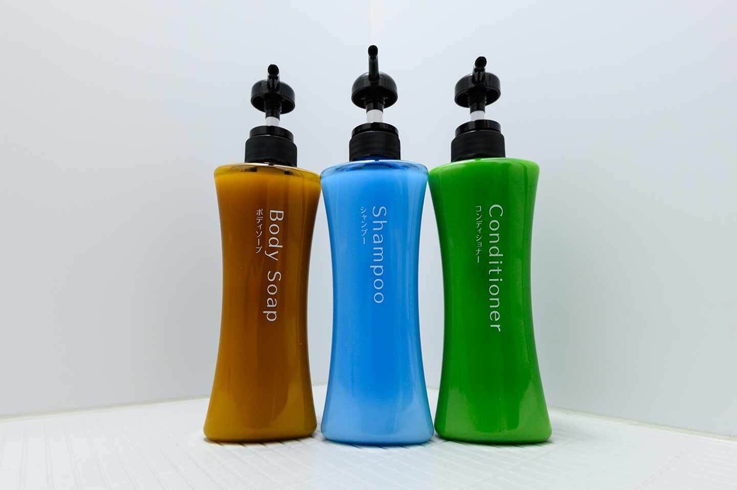 Three bottles of body care products: body soap, shampoo, and conditioner.