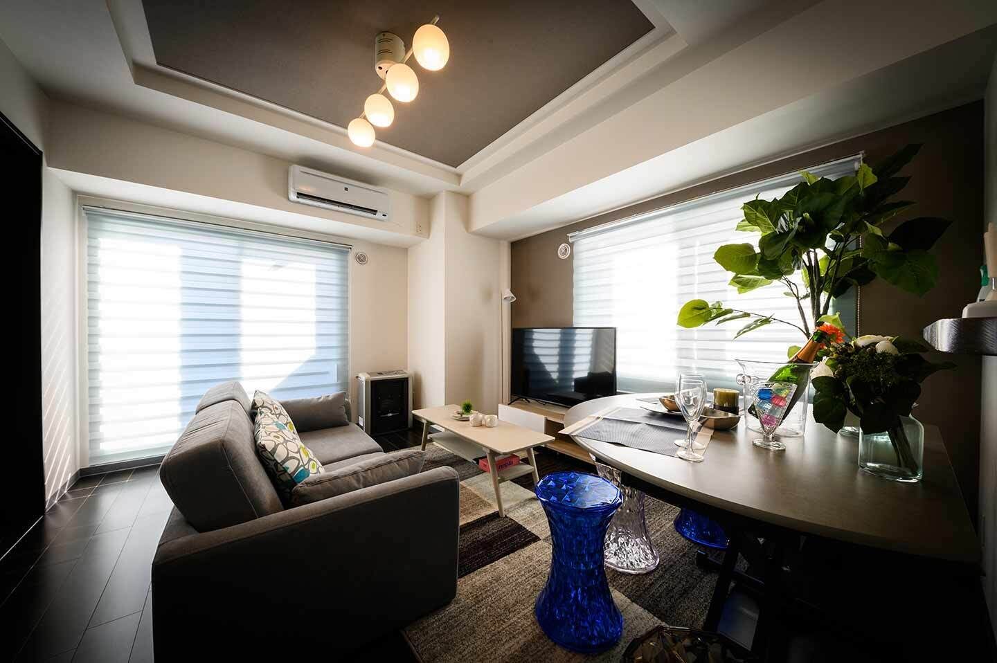 A modern living room with a sofa, TV, dining table, and decorative items.