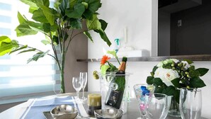 Une table dressée avec une bouteille de champagne, des verres, une bougie et un vase rempli de fleurs.