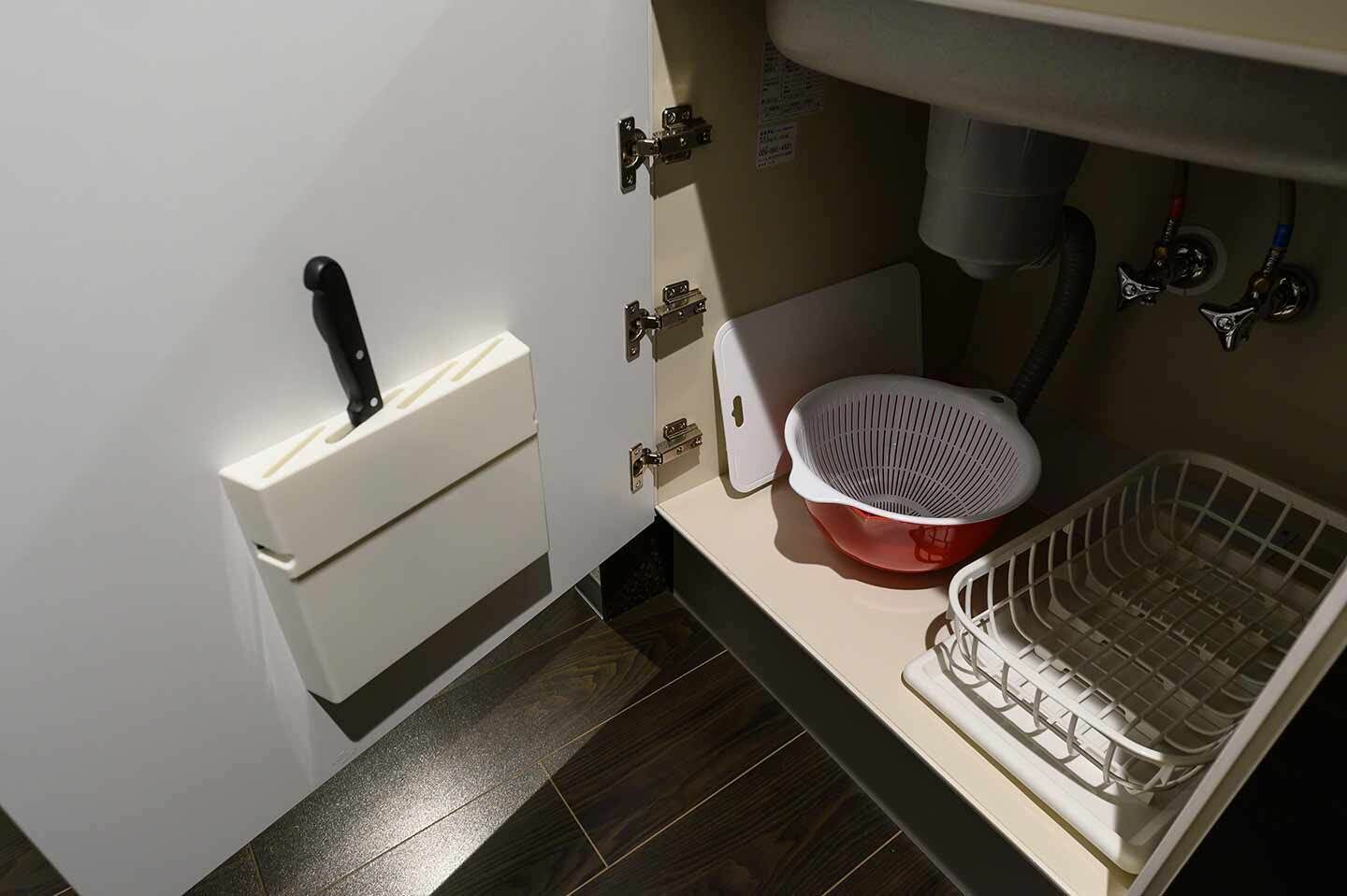 Un baño pequeño con inodoro, lavamanos, colador y tendedero.
