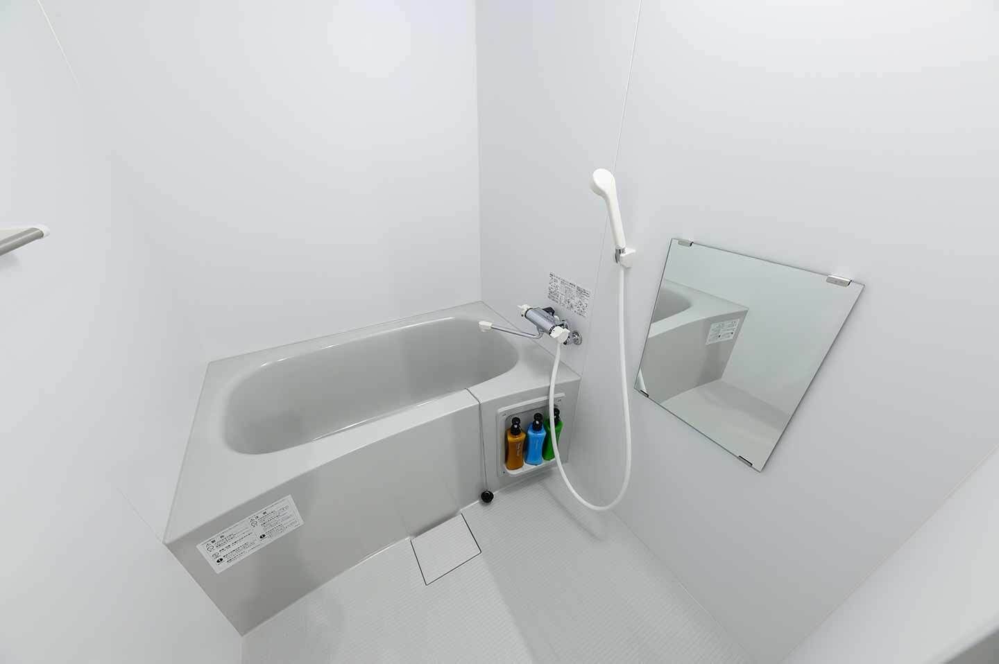 Ein modernes Badezimmer mit Badewanne, Duschbrause und Spiegel.